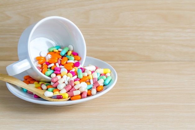 Close-up of multi colored medicines in cup and saucer on wooden table