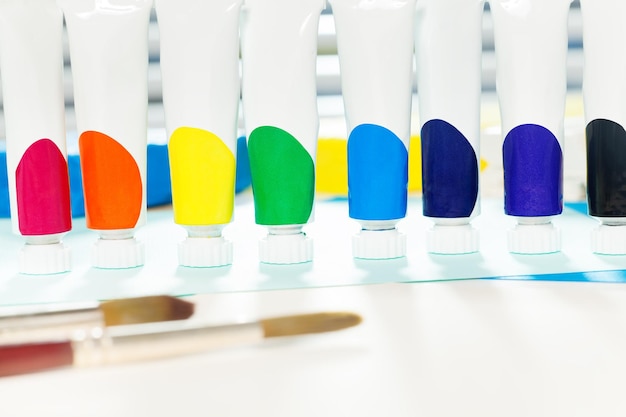 Foto close-up di bottiglie di vernice multicolori con pennelli sul tavolo