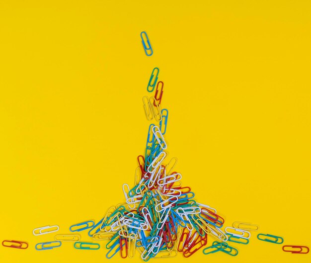 Close-up of multi colored paper clips against yellow background