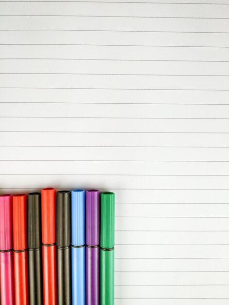 Photo close-up of multi colored pens with book