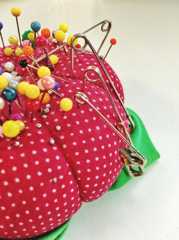 Photo close-up of multi colored pins on pin cushion