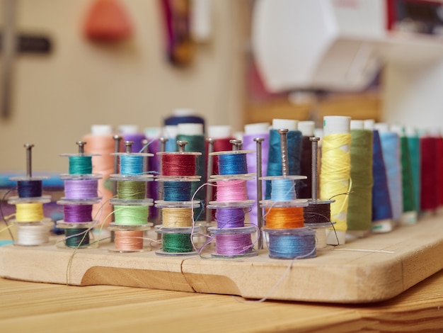 Close-up of multi-colored spools of thread on a wooden stand in a studio