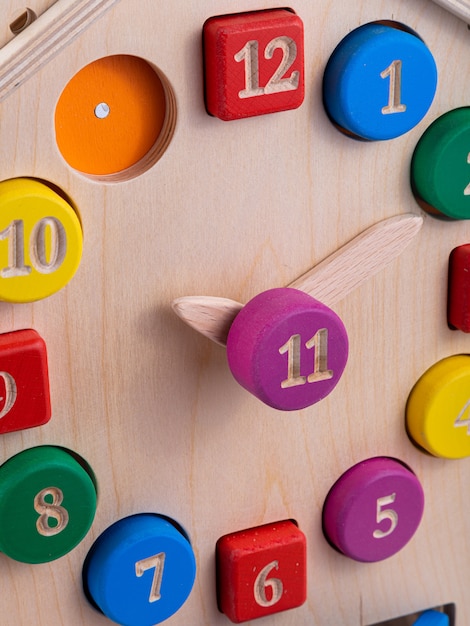Primo piano di un orologio di legno colorato multi sul giocattolo dei bambini