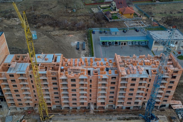 Primo piano su un edificio residenziale multipiano in costruzione dal mattone rosso con una parte di una gru.