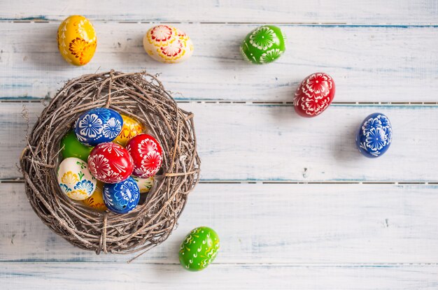 Close-up multicolored easter eggs in basket on wooden table.