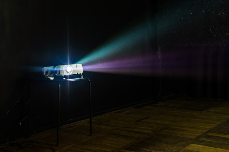 Photo close-up of multimedia projector with colourful rays of light projecting on the screen
