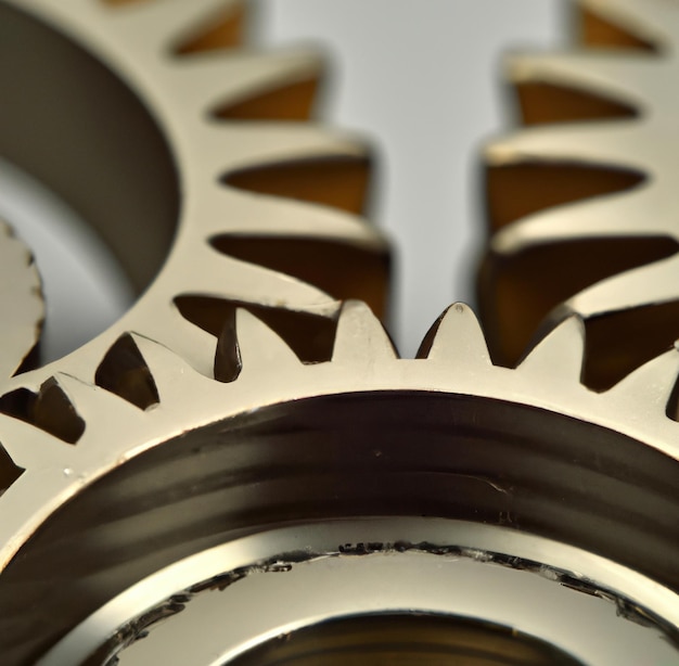 Photo close up of multiple silver cogs and gears on white background