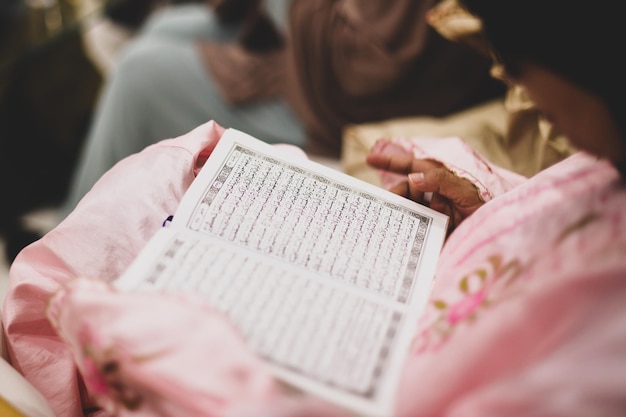 Close up of a muslim woman in a daily prayer at home reciting the holy Quran. Muslim woman studying