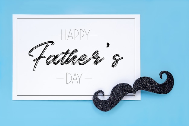 Close-up of a mustache and a card with the phrase happy father's day on blue