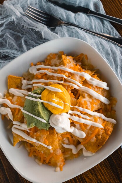 Close up of nachos with cheddar sauce and guacamole vertical photo