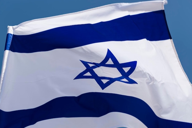 Close up of national Israeli flag develops in a wave in the wind The concept of Israel independence day Yom Haatzmaut Flag Israel with mast waving in the wind National state symbols copy space