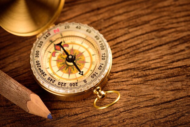 Close-up of navigational compass and pencil on table