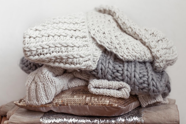 Close up of neatly folded knitted items of pastel color on a light background