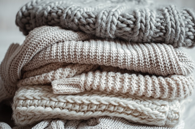 Close up of neatly folded knitted items of pastel color on a light background.