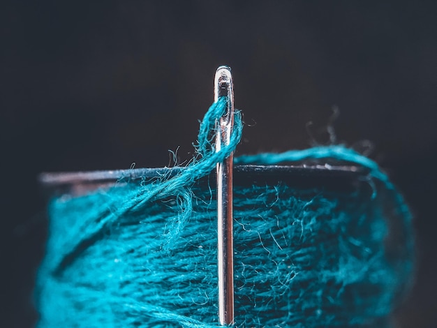 Photo close-up of a needel and yarn reel against black background