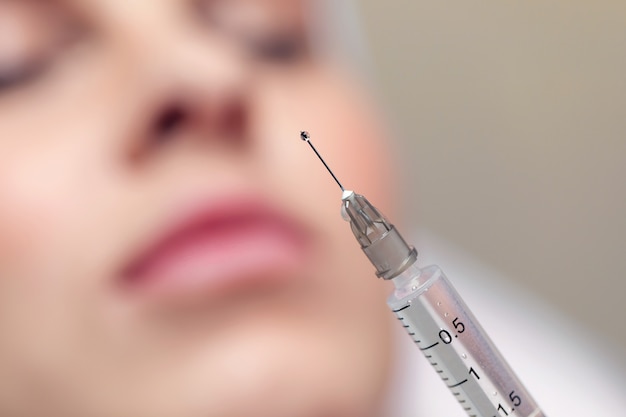 Photo close up needle from an injection in a beauty salon. there is a small drop of liquid at the tip of the needle.