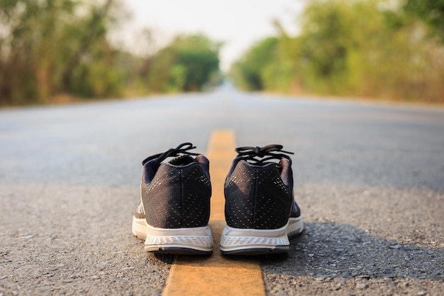 Close up new black running shoes on asphalt road in morning time