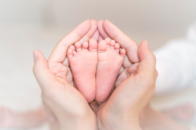 Close up of newborn baby feet on female hands 