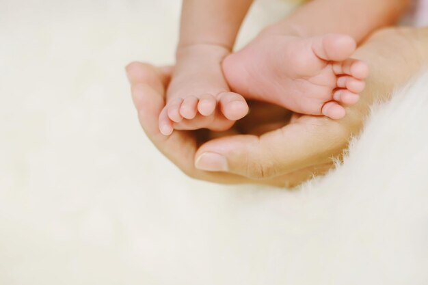 Close up newborn infant baby feet in mother hands babys feet on female