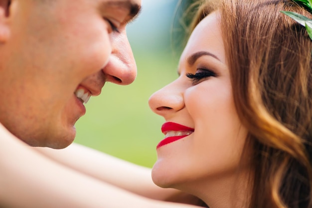 Close-up of the newlyweds' faces, they look at each other and smile. Happy couple.