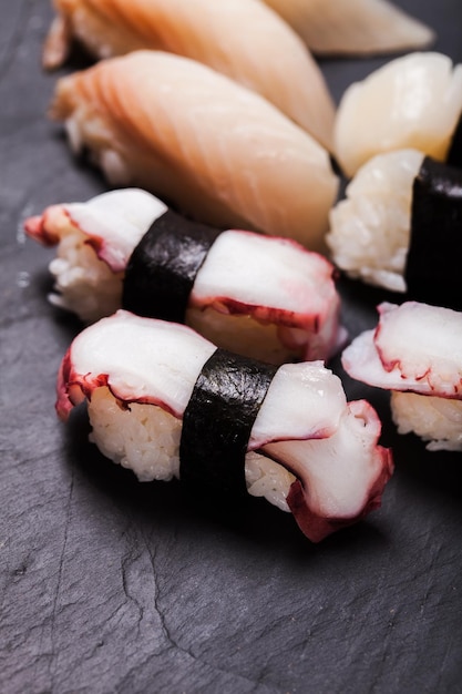 黒いスレートの背景に設定された握り寿司のクローズアップ