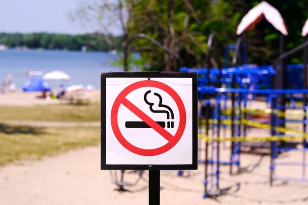 Foto close-up di un cartello di avvertimento contro il fumo vicino al parco giochi sul parco accanto alla spiaggia