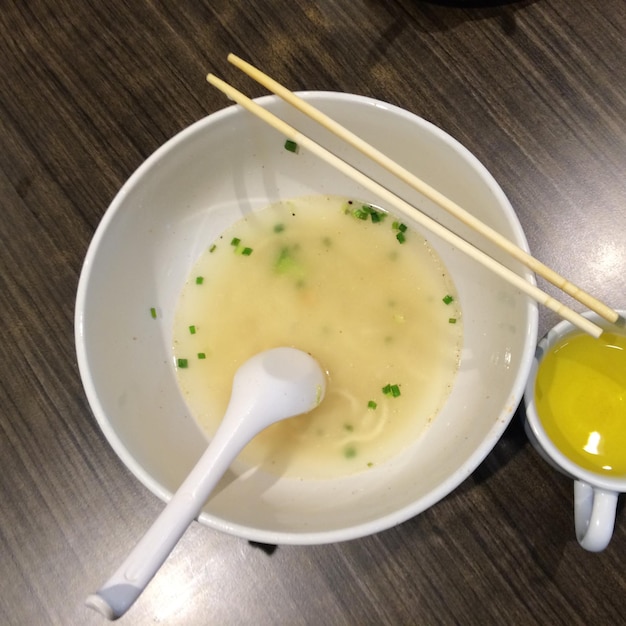 Photo close-up of noodle soup bowl with chopsticks and chamomile tea cup on table