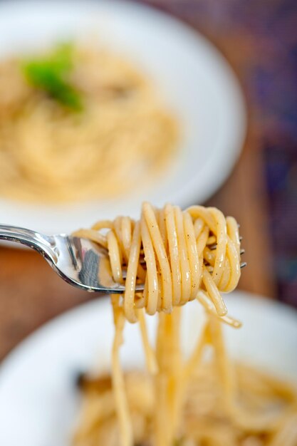 Foto close-up di tagliatelle sulla forchetta sopra il tavolo