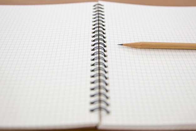 Close-up note book with a pencil on the table.