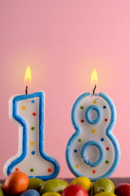 Foto close-up delle candele numero 18 su uno sfondo rosa