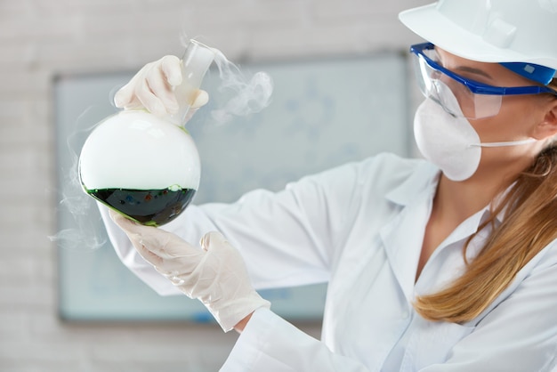 Фото Крупным планом женщина-ученый, держащая жидкие химические образцы, работая в лаборатории, проводящей медицинские исследования.
