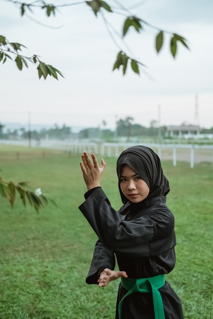 자연에서 측면 자세 움직임과 함께 Pencak Silat 유니폼을 입고 가려져 여자의 닫습니다