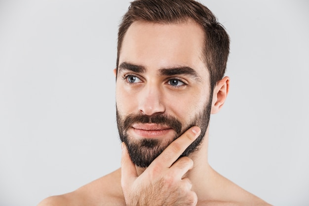 Фото Крупным планом молодой красивый бородатый мужчина без рубашки, стоящий изолированно над белой