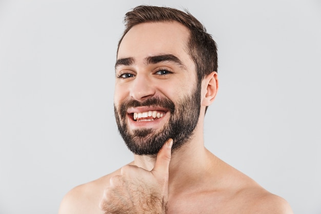 Фото Крупным планом молодой красивый бородатый мужчина без рубашки, стоящий изолированно над белой