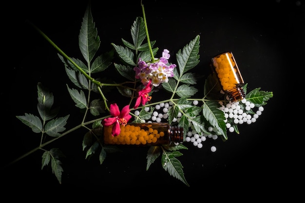 Фото Близкий план бутылок и листьев с лекарствами на черном фоне