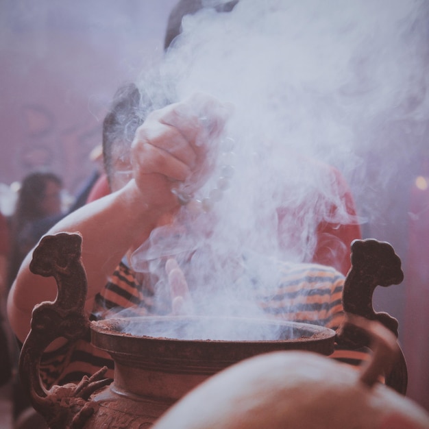 写真 煙の中の寺院で祈っている男の子のクローズアップ