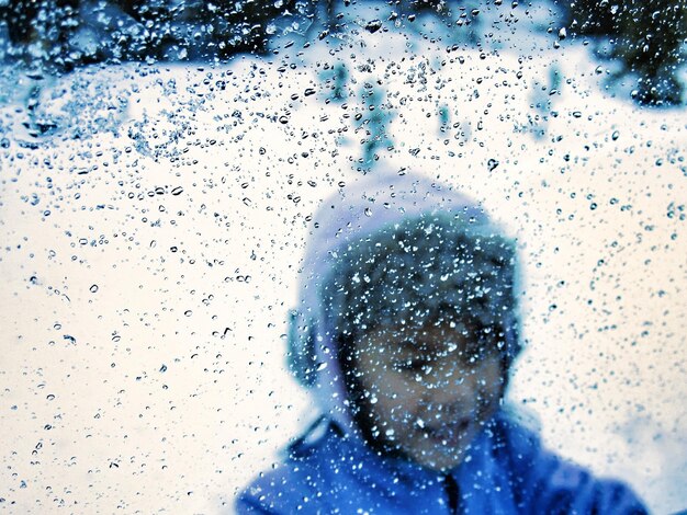 写真 湿った窓から見た少年をクローズアップ