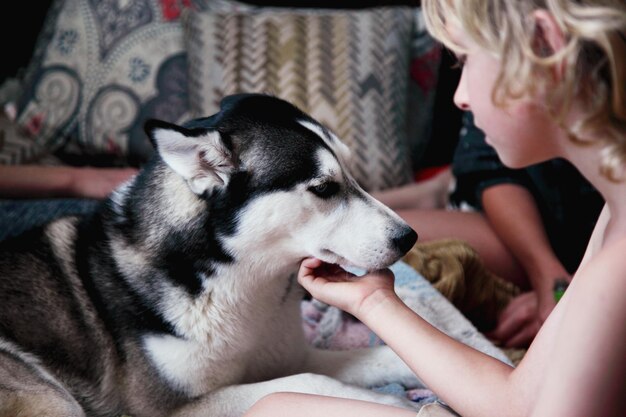 写真 ベッドの上でシベリアン・ハスキー犬に触れる男の子のクローズアップ