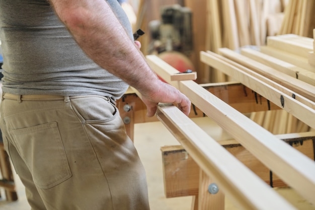 Фото Крупный план рук плотников с доской в столярной деревообрабатывающей мастерской.