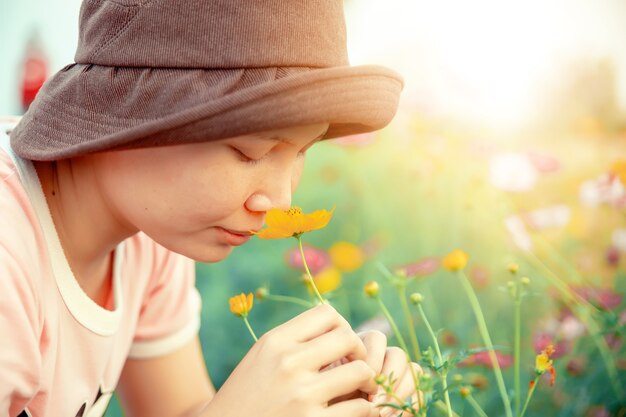 庭でコスモスの花の匂いがする陽気な女性のクローズアップ。