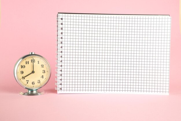사진 분홍색 배경 에 있는 시계 와 노트 패드 의 클로즈업