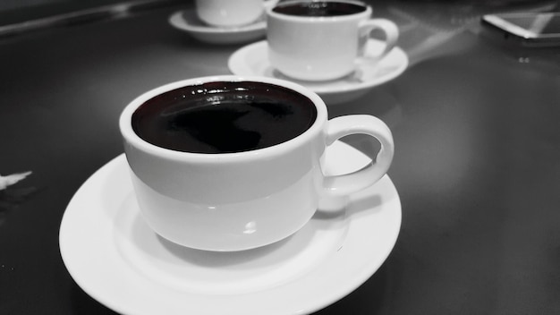 Фото Клоуз-ап чашки с кофе на тарелке над столом