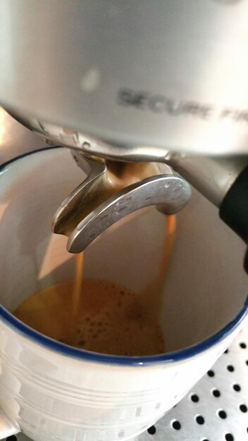 写真 カフェでエスプレッソメーカーからカップにコーヒーを注ぐクローズアップ
