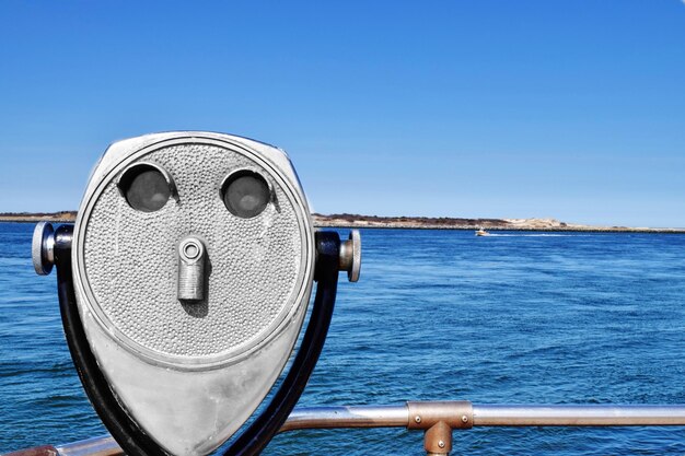 Фото Близкий план бинокля с монетой на море на фоне ясного голубого неба
