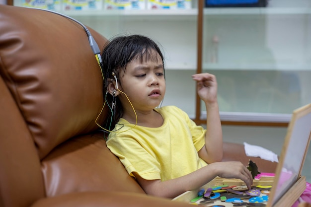 写真 家のソファーに座っている頭に電極をかぶった可愛い女の子のクローズアップ