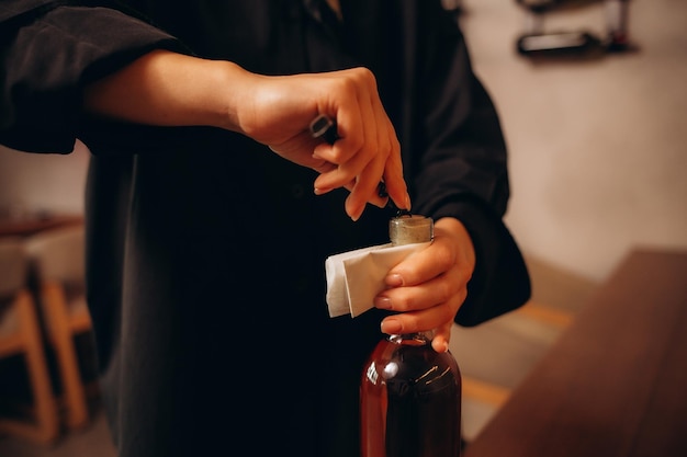 사진 은 와인 한 병을 들고 검사하는 귀여운 젊은 술집 직원의 클로즈업.