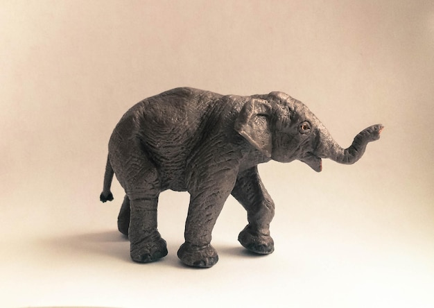 Фото Клоуз-ап статуэтки слона на бежевом фоне
