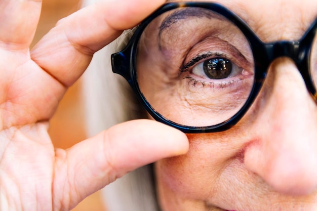 Фото Близкий взгляд на пожилую женщину, надевающую очки