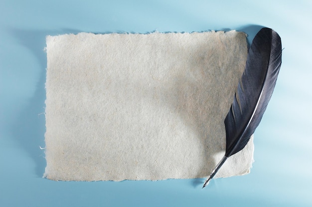 Фото Близкий план перья с бумагой на синем фоне
