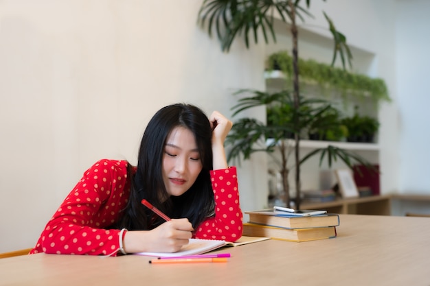 写真 ノートにメモを取る女子学生のクローズアップ。